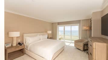 Una habitación de hotel con una cama grande, un escritorio, una silla, un televisor y vistas al océano.
