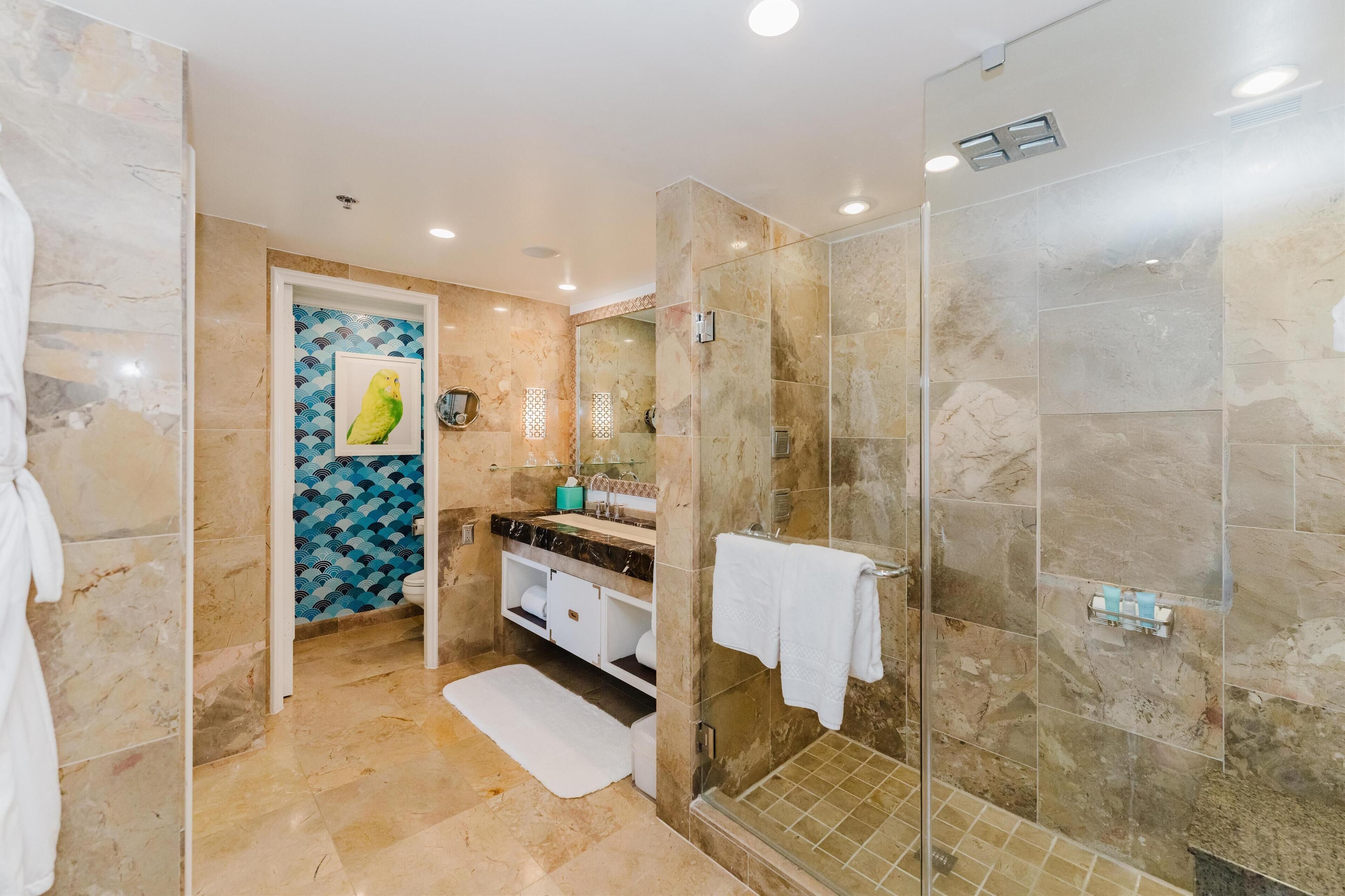 A modern bathroom with a glass shower enclosure, marble flooring, and a sink with a towel rack.