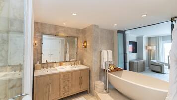 Un baño moderno con un espejo grande, dos lavamanos, una bañera y muebles de madera.