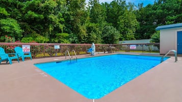 Una piscina amb una zona tancada, cadires blaves i una caseta de socorristes.