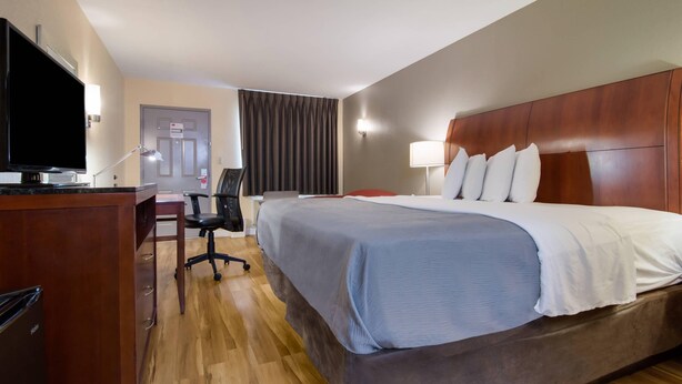 Una habitación de hotel con una cama grande, un escritorio con televisor y una silla.