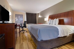 A hotel room with a large bed, a desk with a television, and a chair. - Econo Lodge Battleboro - Rocky Mount I-95 (Battleboro)