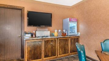 Een hotelkamer met een houten kast, een televisie, een minibar en een teal-kleurige stoel.