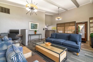 Ein modernes Wohnzimmer mit einem blauen Sofa, einem Glastisch und einem Fernseher.