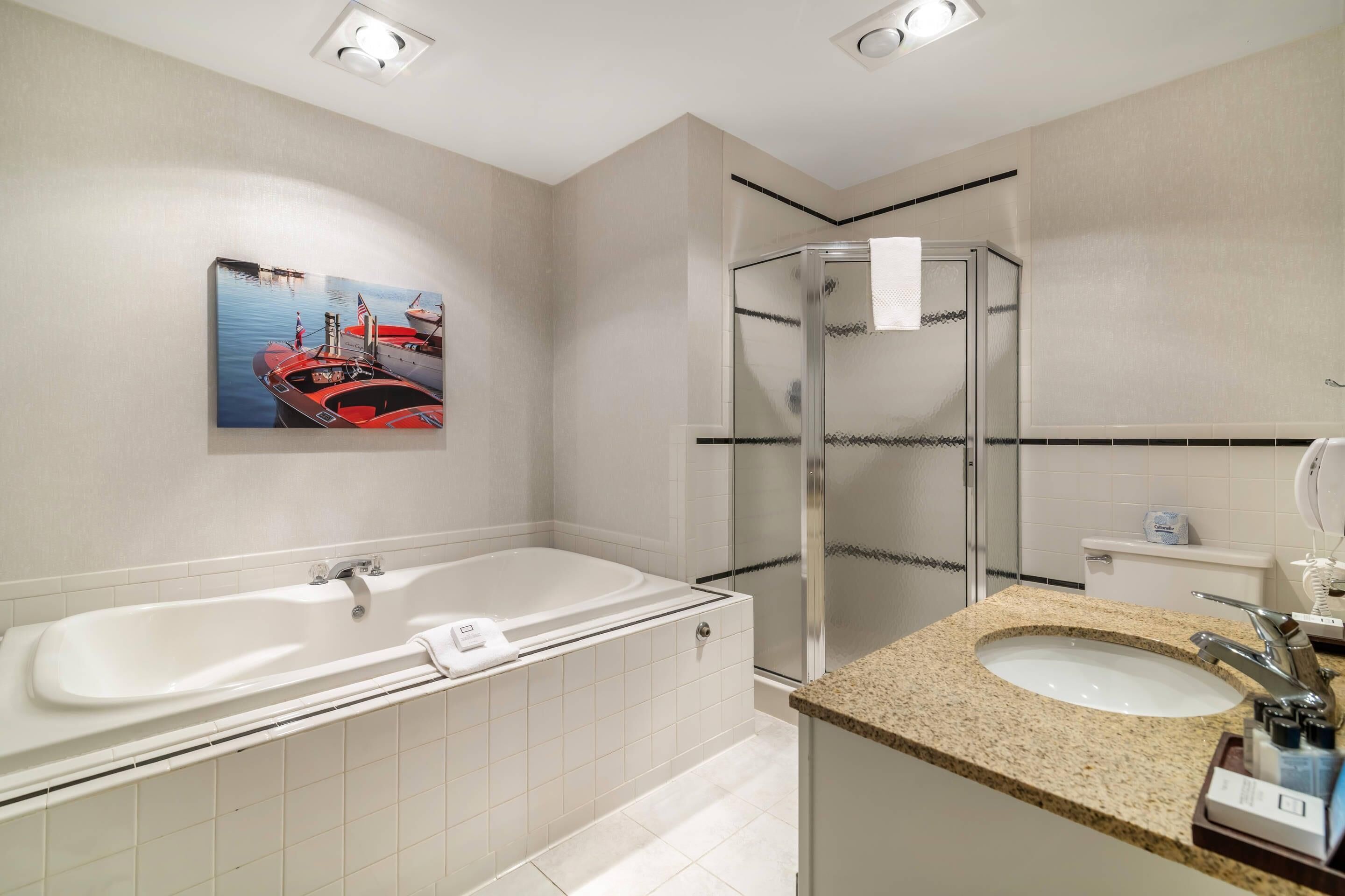 A modern bathroom with a bathtub, a glass shower enclosure, and a sink with a granite countertop.