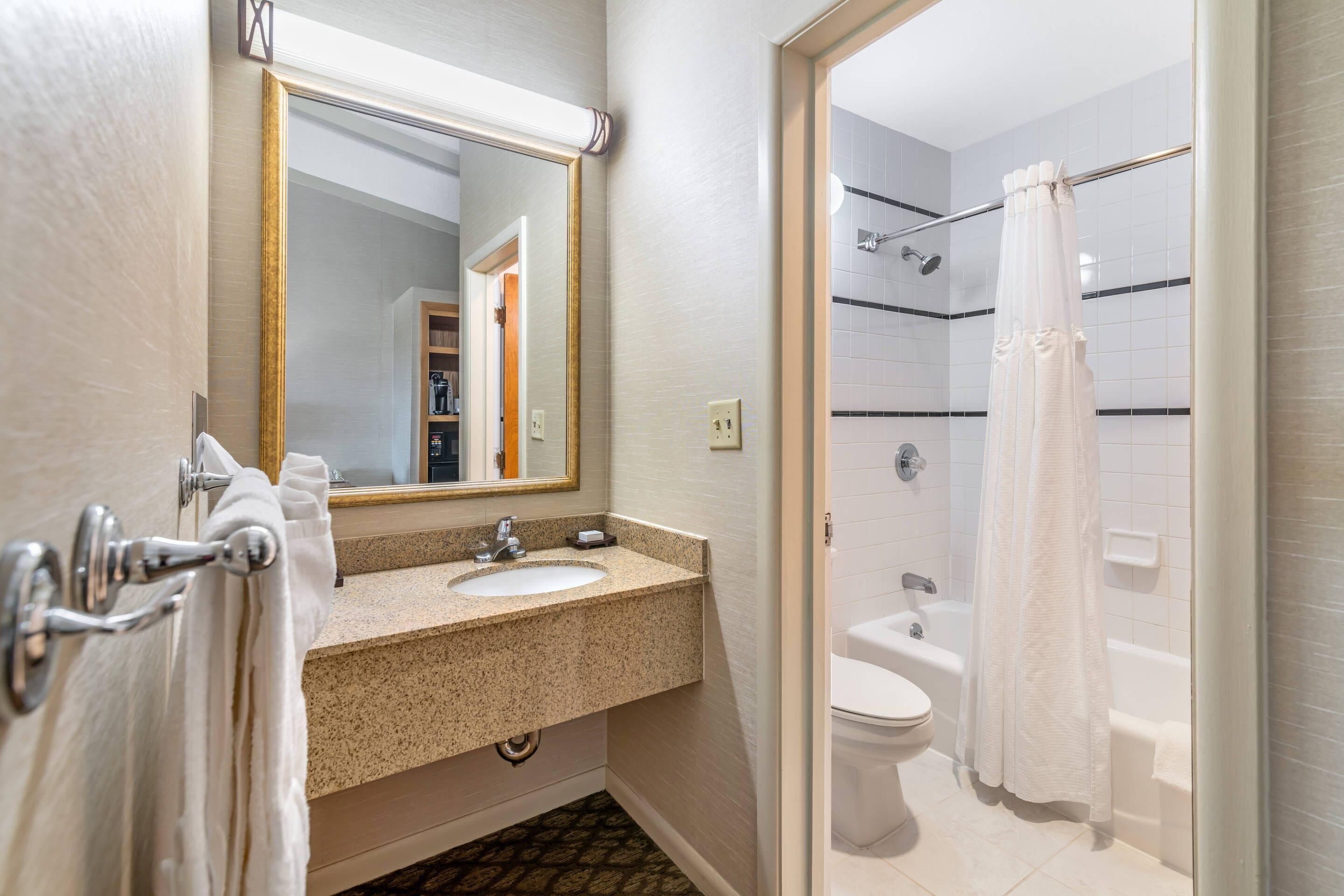 A bathroom with a sink, mirror, toilet, and shower.