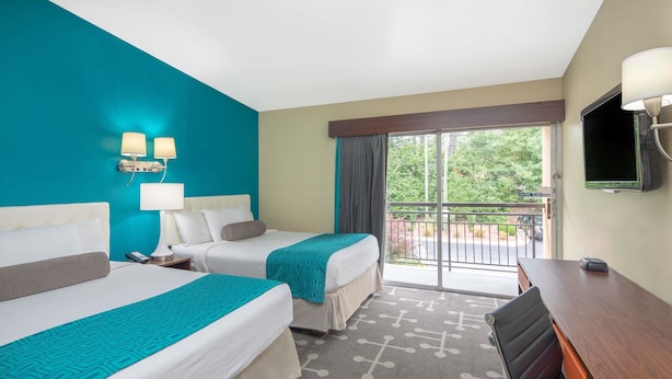 A hotel room with two beds, a desk, a TV, and a balcony with a view of trees. - Howard Johnson by Wyndham Athens (Athens)