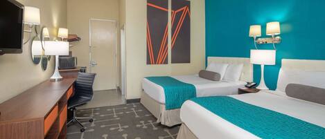A hotel room with two beds, a desk, a chair, and a TV.