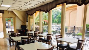 A restaurant with indoor and outdoor seating, a television, and a view of the outside. - Howard Johnson by Wyndham Athens (Athens)
