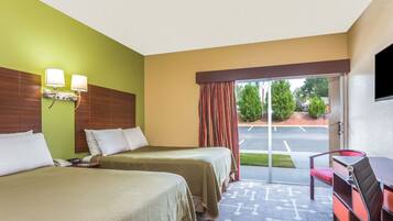 A hotel room with two beds, a desk, and a chair.