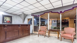 A reception area with a wooden reception desk, two patterned armchairs, and a glass partition. - Howard Johnson by Wyndham Athens (Athens)