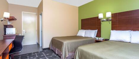 A hotel room with two beds, a desk with a chair, a telephone, and a wall-mounted light fixture.