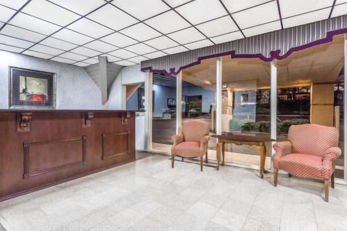 A reception area with a wooden desk, two patterned chairs, and a tiled floor.