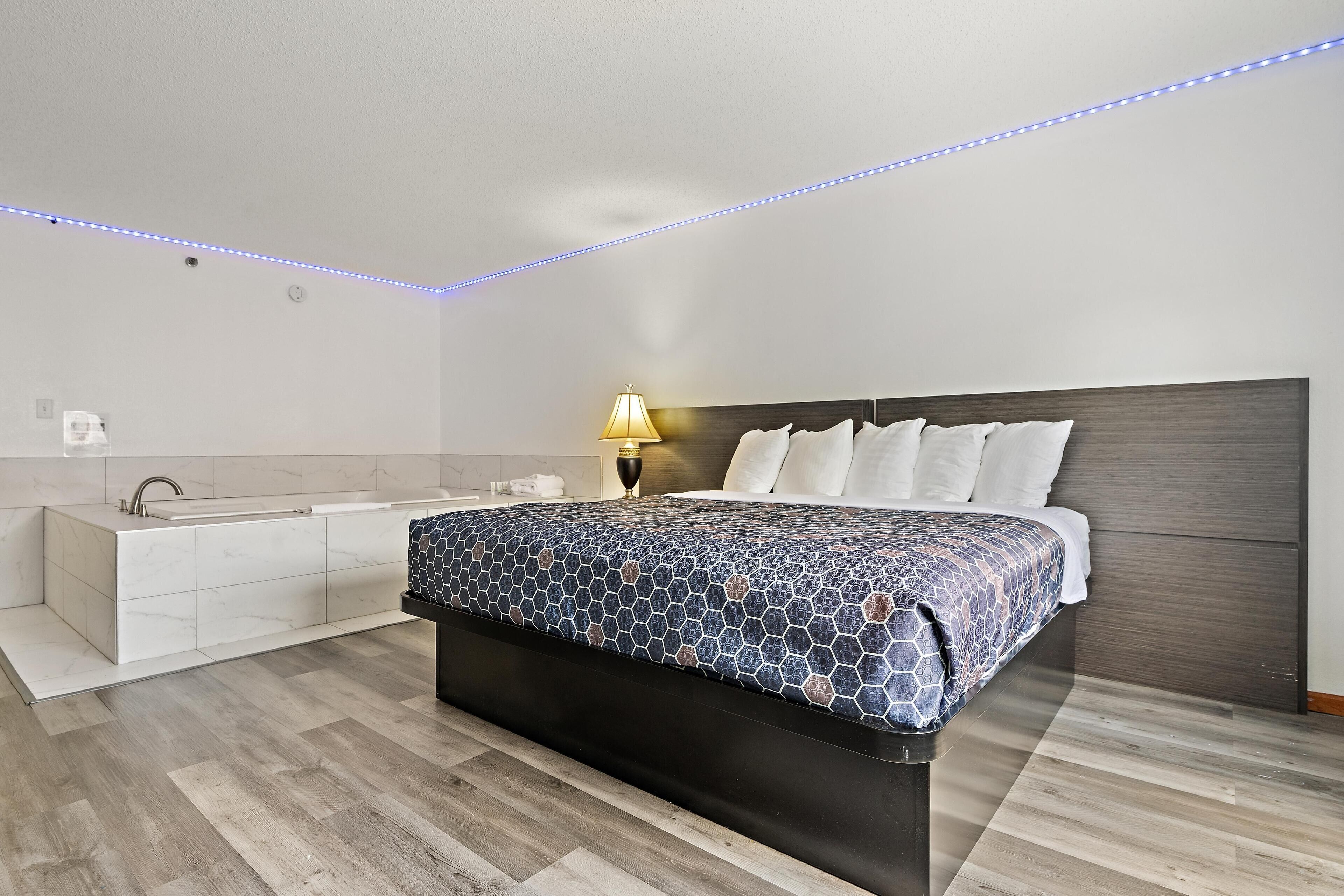 A modern bedroom with a large bed, a bedside table, a nightstand, a lamp, and a built-in bench.
