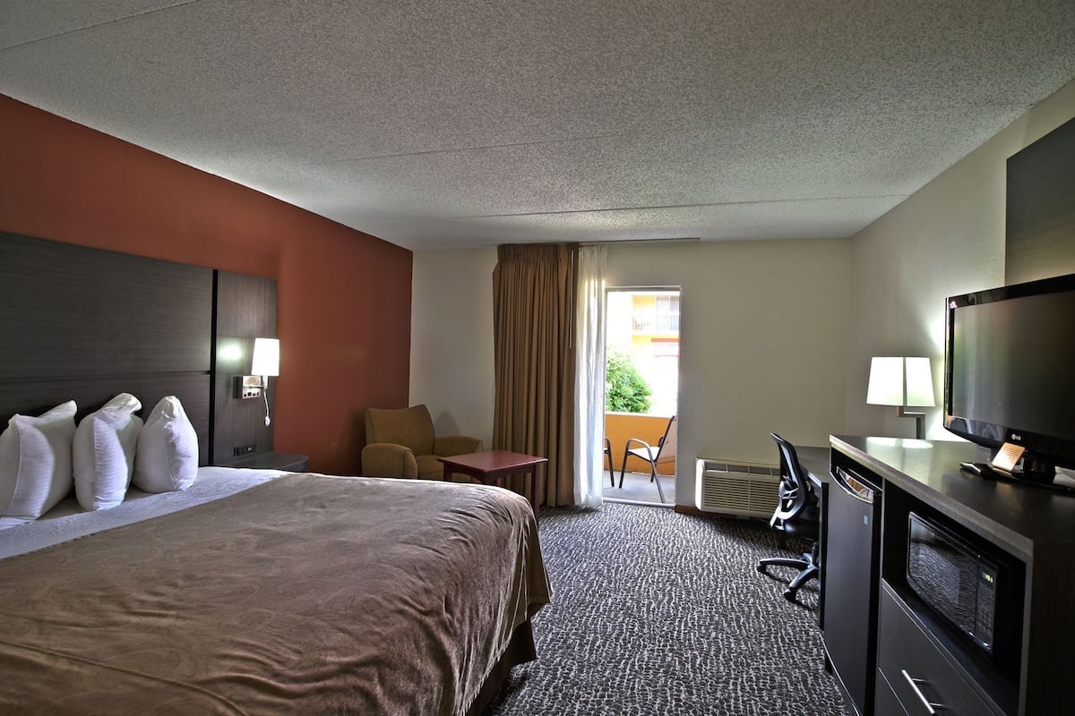 A hotel room with a bed, a desk, a television, and a chair.