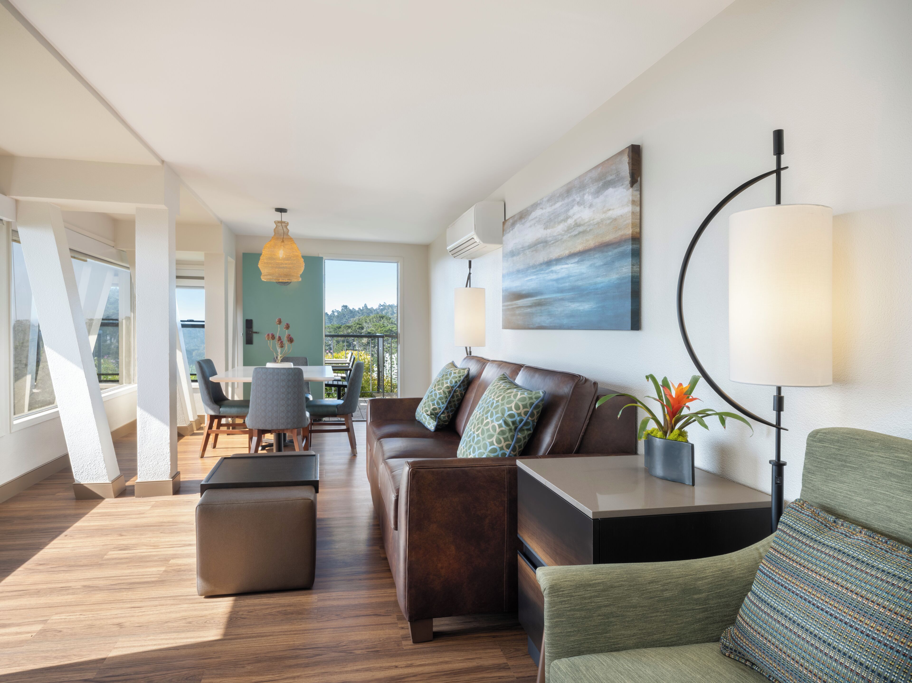 A modern living room with a sofa, ottoman, and a dining area with a table and chairs.