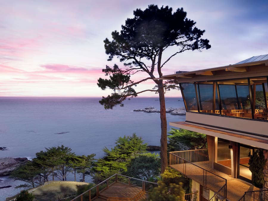 A modern building with large windows overlooking a coastal area.