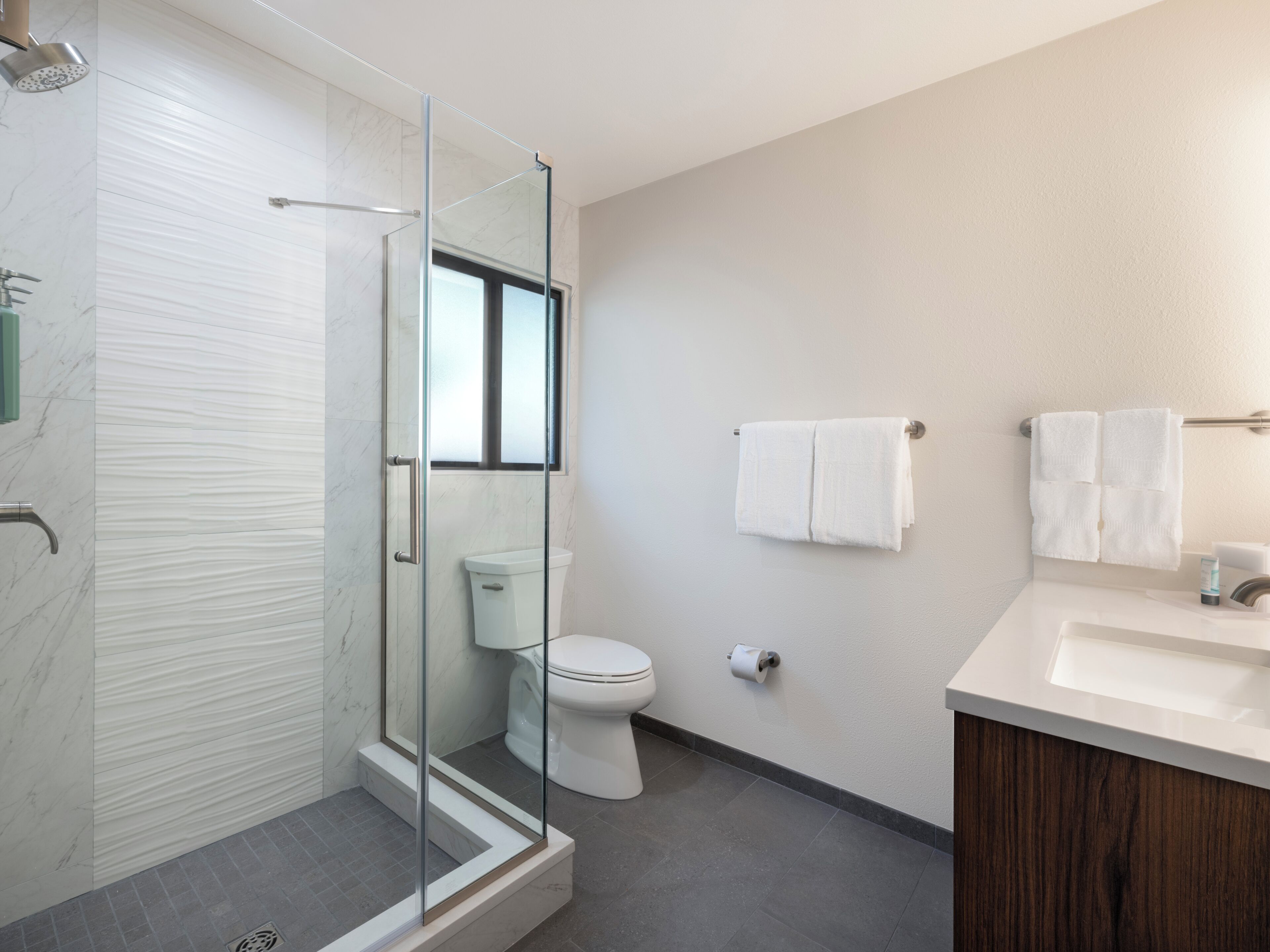 Une salle de bain moderne avec une douche à parois de verre, des toilettes, un lavabo et un miroir.