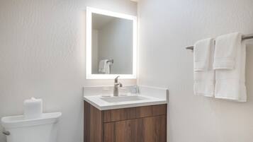 A modern bathroom with a white sink, wooden vanity, and a toilet.