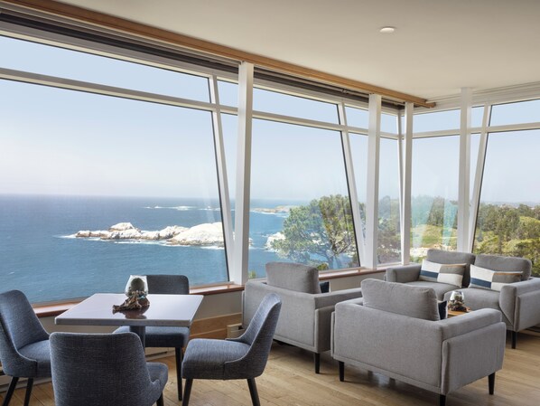 A modern interior with large windows offering a view of the sea and rocky coastline. - Hyatt Carmel Highlands (Carmel)