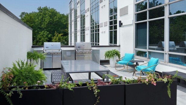 An outdoor patio with a grill, seating area, and potted plants. - TownePlace Suites by Marriott Niagara Falls Canada (Niagara Falls)