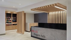 A reception area with a 'HELLO Niagara Falls' sign, wooden paneling, and a shelf with snacks. - TownePlace Suites by Marriott Niagara Falls Canada (Niagara Falls)