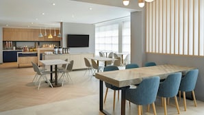 A modern kitchen with wooden cabinets, a central island, and a dining area with a large table and chairs. - TownePlace Suites by Marriott Niagara Falls Canada (Niagara Falls)