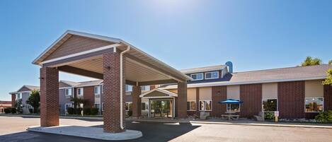 A modern building with a covered entrance, brick pillars, and a clear sky.