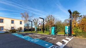 A parking area with designated spaces for electric vehicles and disabled parking, marked with clear signage and symbols. - B&B HOTEL Blois Nord Vallee Maillard (Blois)