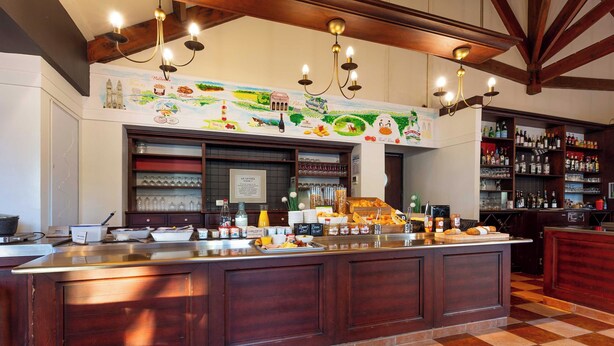 A bar area with a checkered floor, wooden beams, and a mural depicting food and wine. - B&B HOTEL Blois Nord Vallee Maillard (Blois)