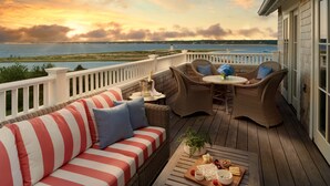 A deck with a wicker sofa, a table with a bottle of champagne, and a tray of snacks. - Harbor View Hotel (Edgartown)