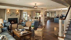 A spacious living room with a fireplace, comfortable seating, and a staircase leading to another area. - Harbor View Hotel (Edgartown)