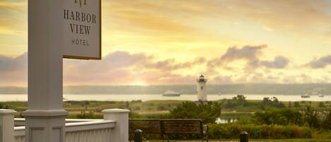 A sign for the Harbor View Hotel with a view of the sea and a lighthouse in the background.