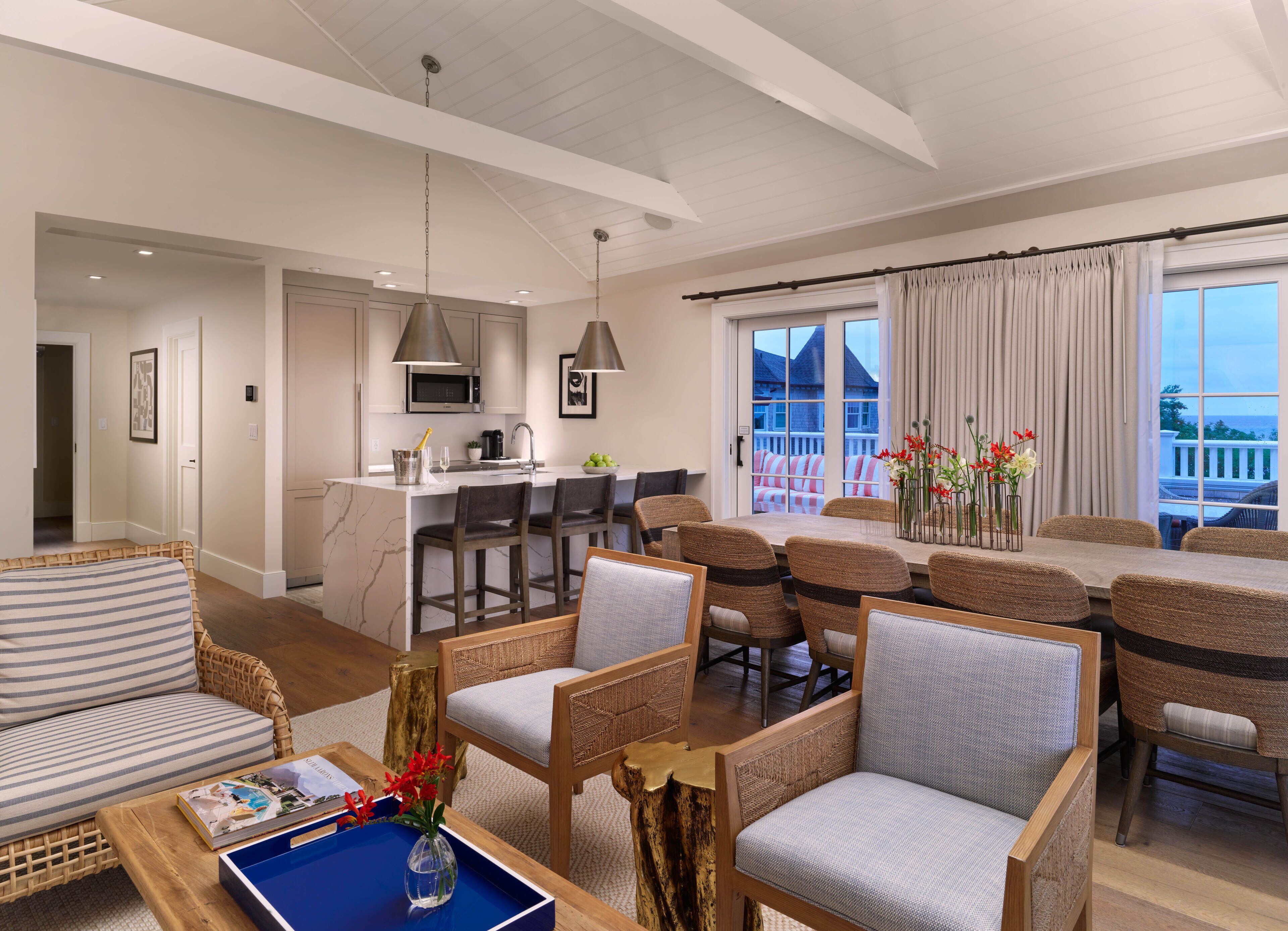 A modern living room with a dining area, kitchen, and a balcony with a view.