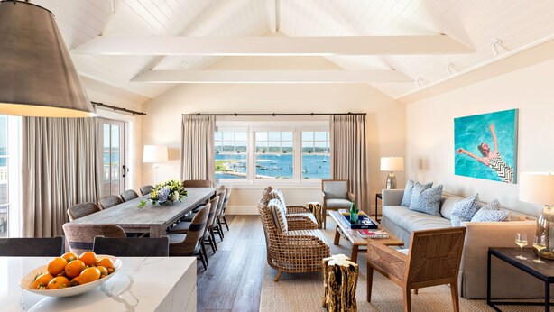 A spacious living area with a dining table, sofas, and a view of the sea. - Harbor View Hotel (Edgartown)