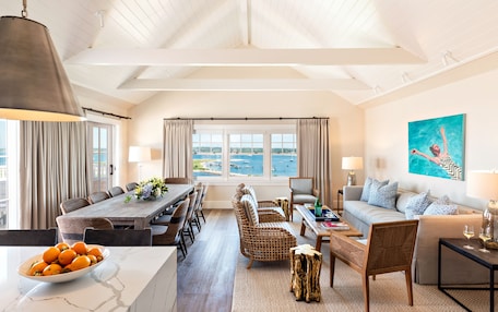 A spacious living area with a dining table, sofas, and a view of the sea.