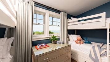 Cozy bedroom with a bunk bed arrangement, large window, and a bedside table with a plant and books.