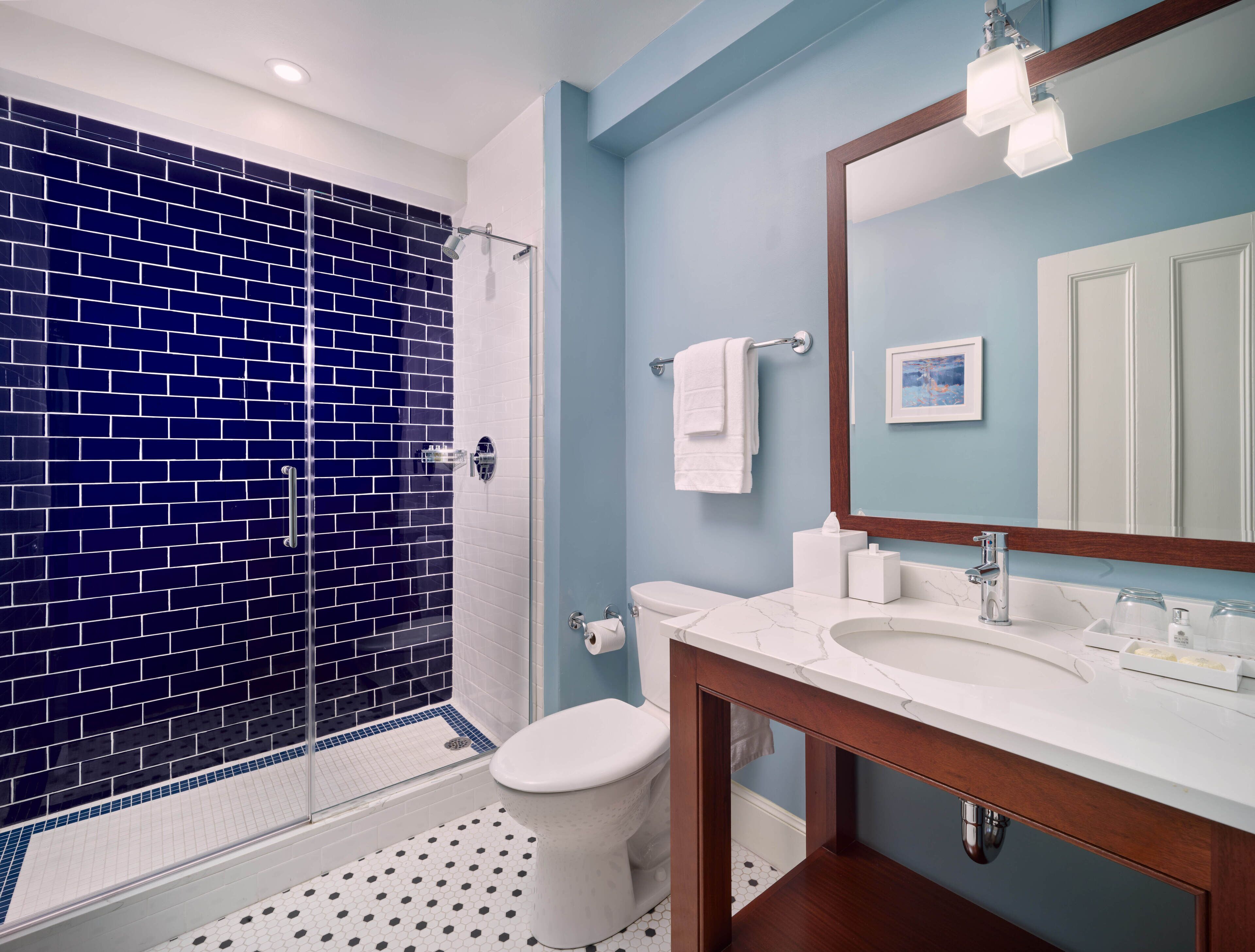 Un bagno con doccia a vetro, un WC bianco, un lavabo in marmo e uno specchio grande.