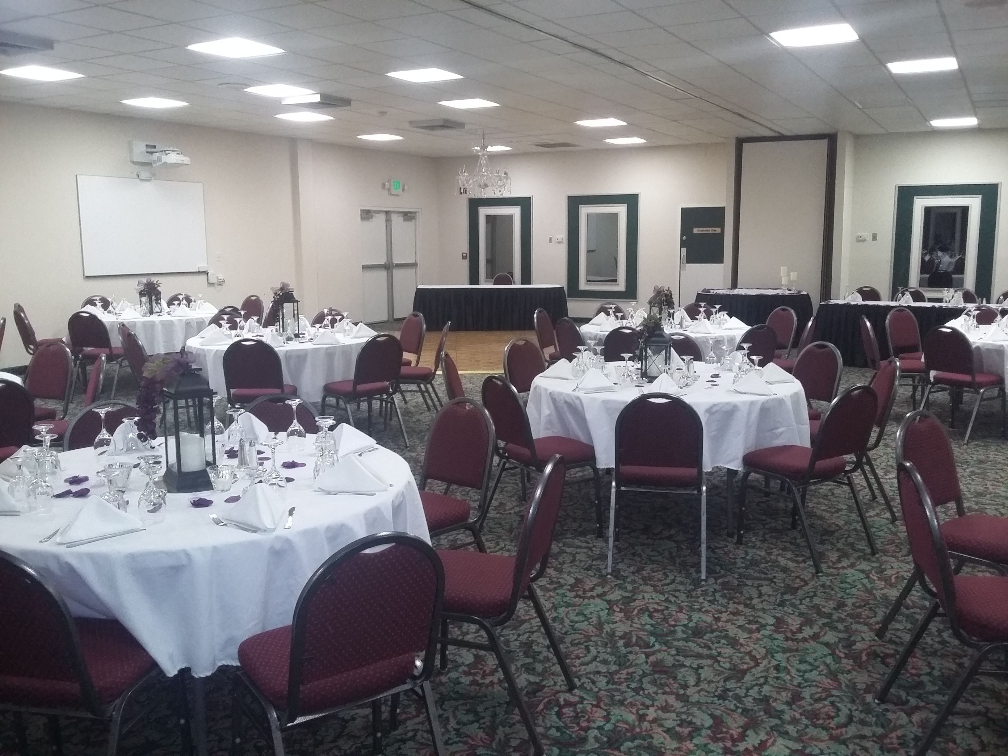 Una sala de conferències amb taules rodones, cadires vermelles i tovallons blancs.