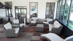 A lobby with wicker furniture, a patterned carpet, and large windows.