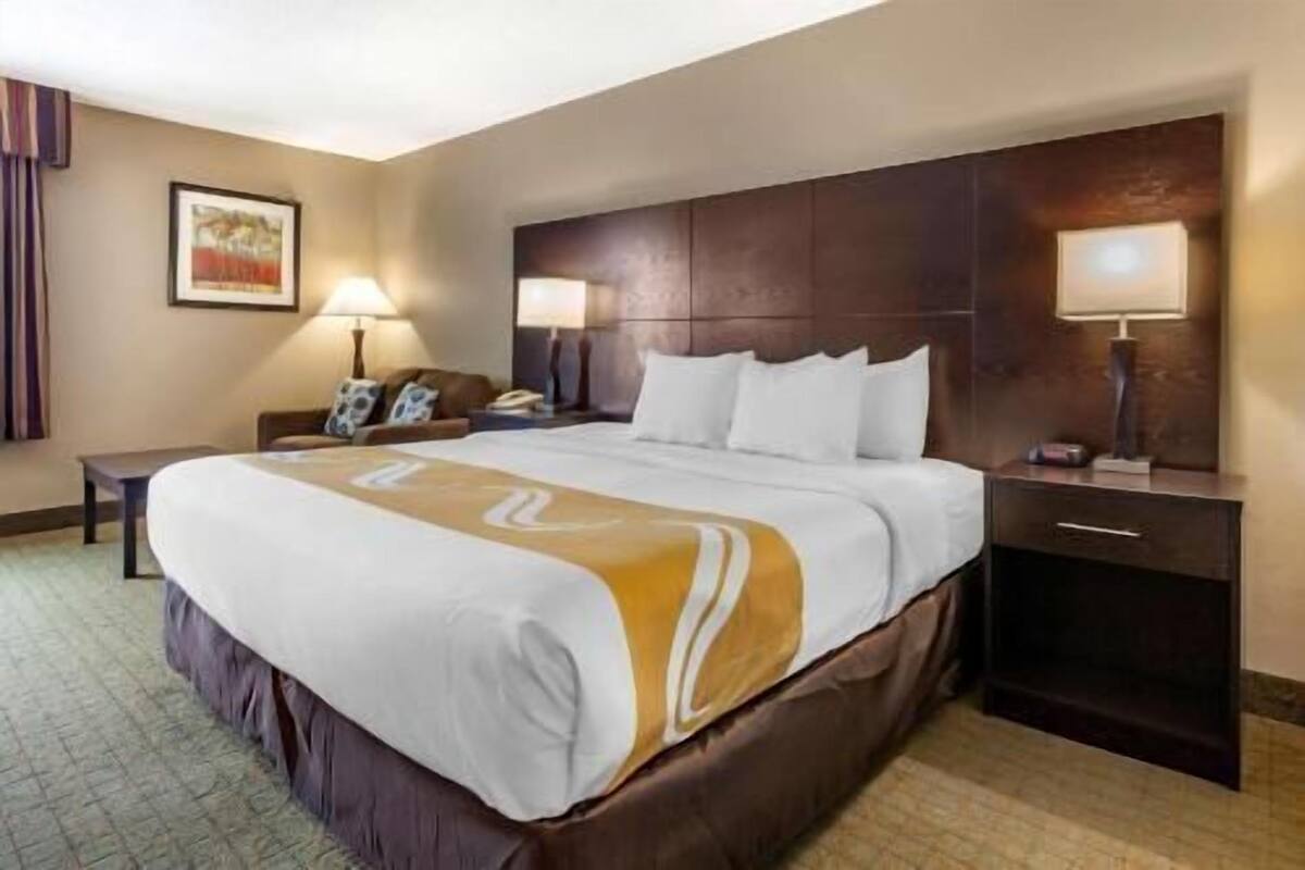 A hotel room with a large bed, bedside tables, a desk, and a headboard.