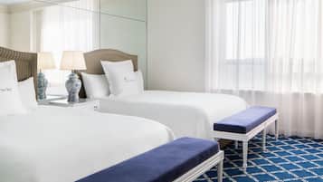 A hotel room with two beds, a bench, a lamp, and a large mirror.