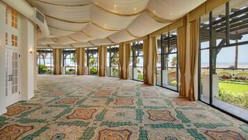 A spacious hall with patterned carpet, large windows, and a view of the beach.