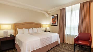 Camera d'albergo con un letto grande, due comodini con lampade, una poltrona rossa e un quadro appeso al muro.