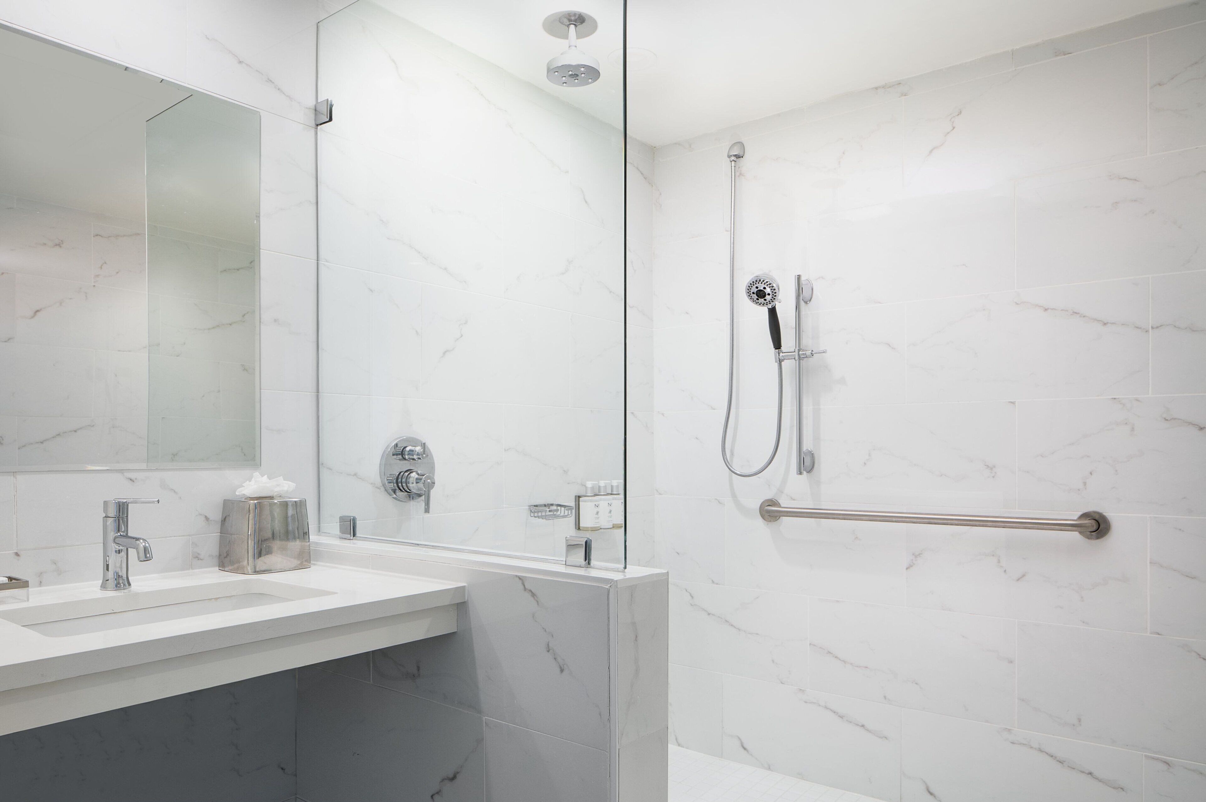 Une salle de bain moderne avec une douche à parois de verre, un meuble-lavabo avec un miroir et un porte-serviettes.