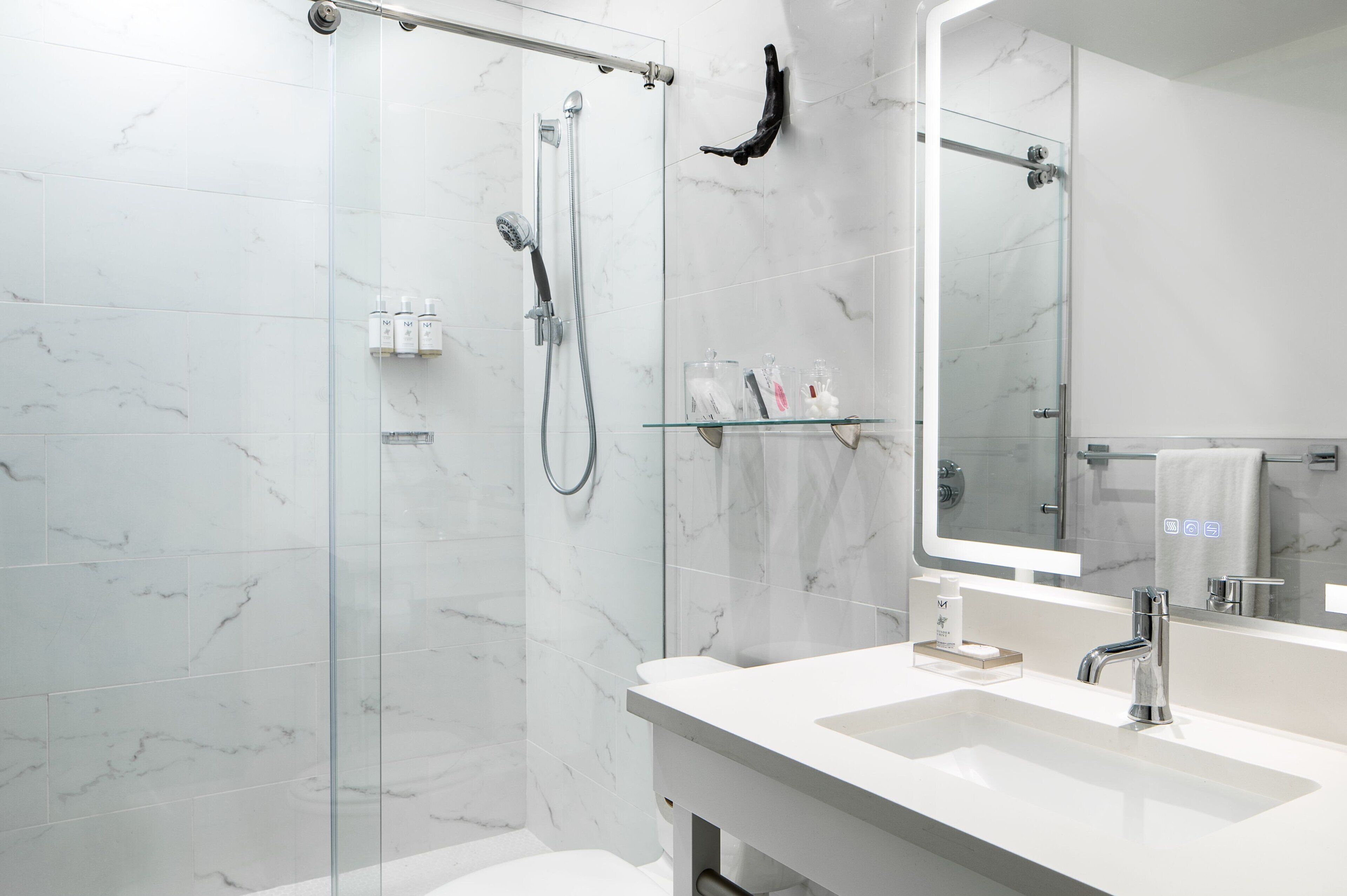 A modern bathroom with a glass shower enclosure, a white sink, and a large mirror.