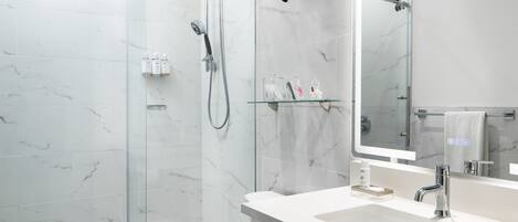 Un baño moderno con cabina de ducha de vidrio, un lavabo blanco y un espejo grande.