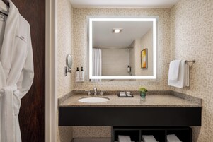 Un baño moderno con un espejo grande, un lavabo y un mueble de tocador oscuro.