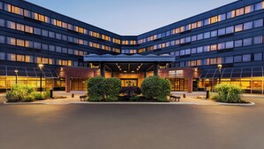 A modern hotel with a curved facade, large windows, and a well-lit entrance.