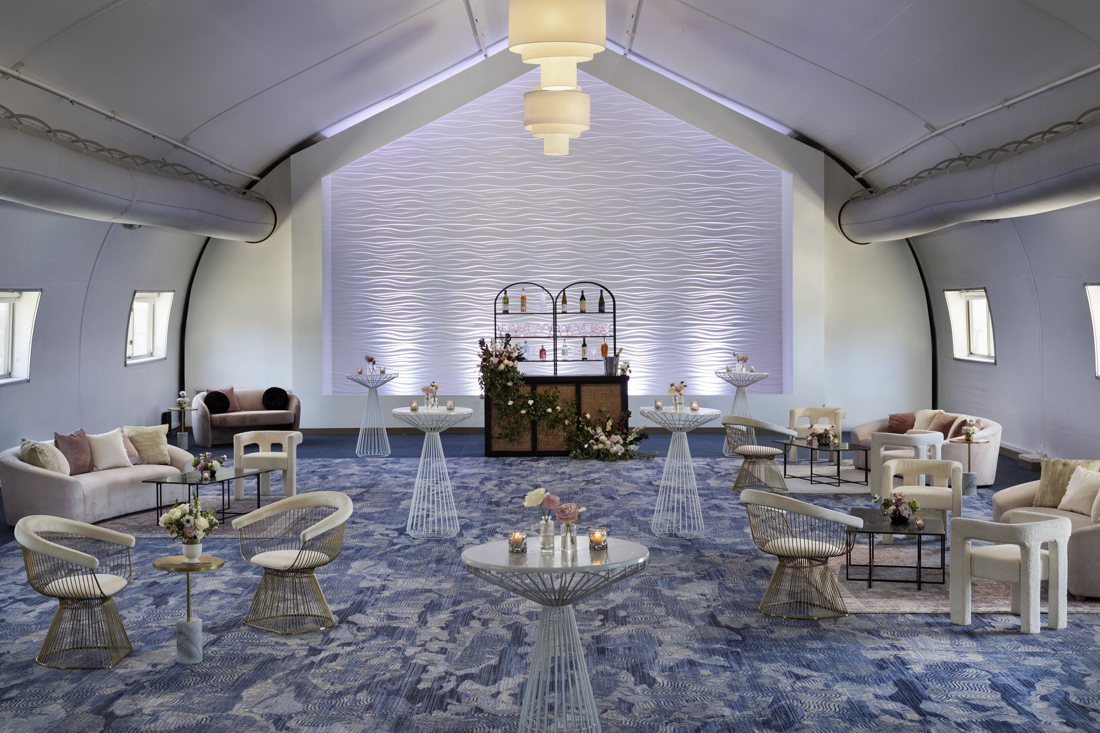 A spacious, modern lounge area with a high ceiling, multiple seating arrangements, and a decorative centerpiece.